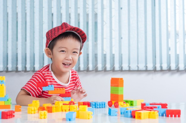 cute boy playing with colorful plastic bricks at the table in the children s room 1249 494